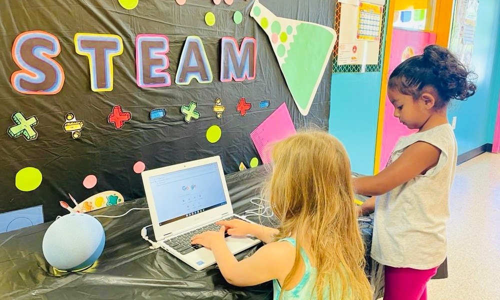 two kids making art with colored cut-outs on a table
